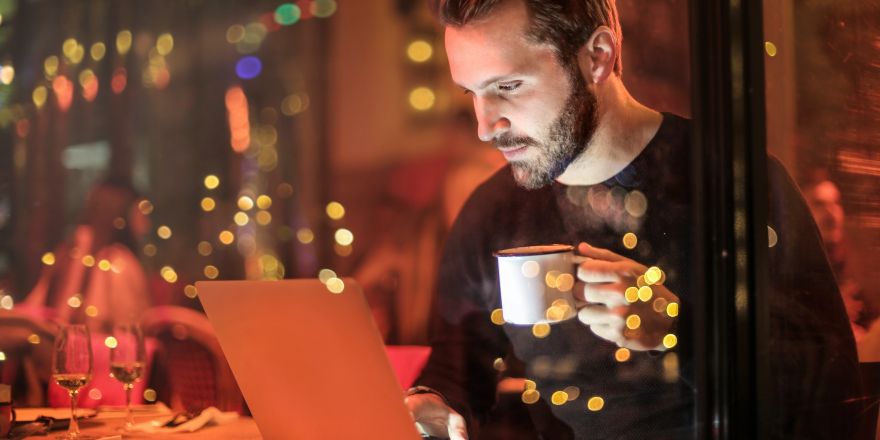 Man met koffie die op laptop kijkt