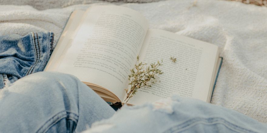 Persoon leest boek op een kleedje