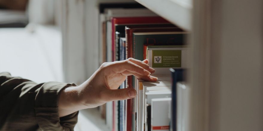 Hand pakt boek uit kast