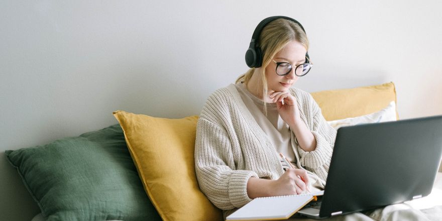 Vrouw achter laptop met koptelefoon op haar hoofd