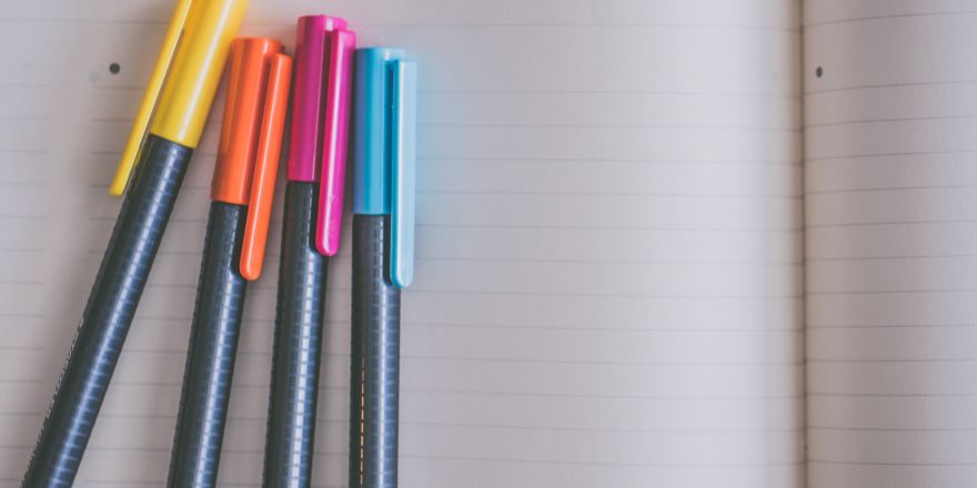 Gekleurde pennen op een notitieboek