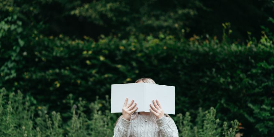 Persoon met boek voor gezicht