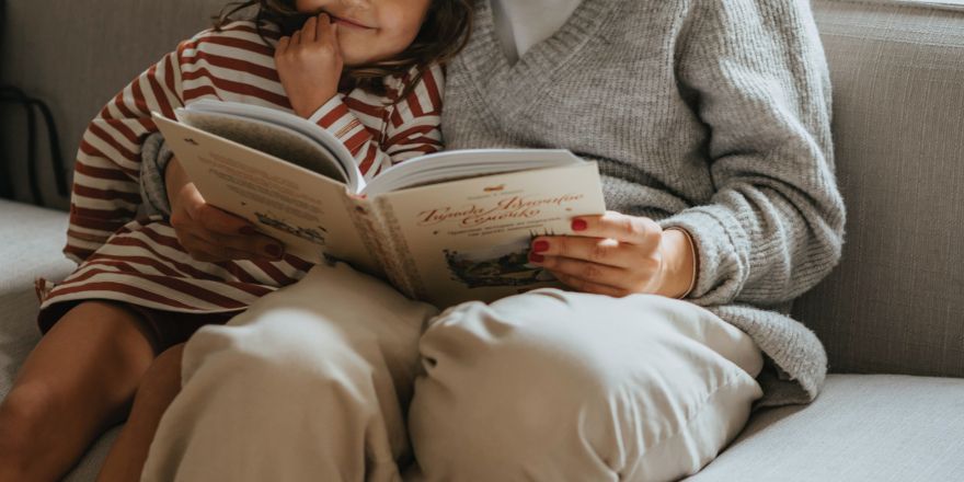 Moeder leest dochter voor op de bank