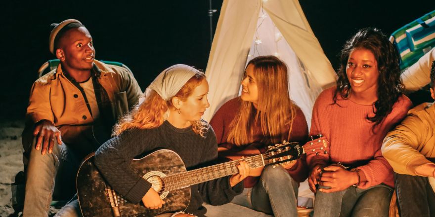 Groep vrienden zingt rond een kampvuur