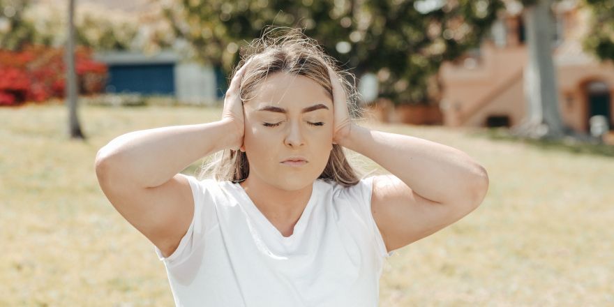 Vrouw drukt handen tegen oren 