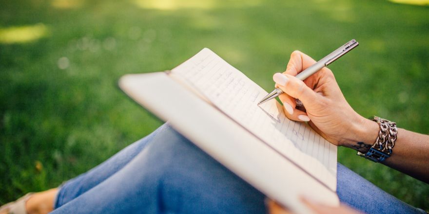 Persoon schrijft in notitieboekje in het park