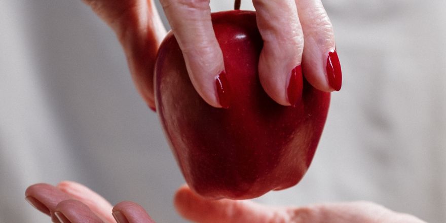 Hand geeft een rode appel aan een andere hand