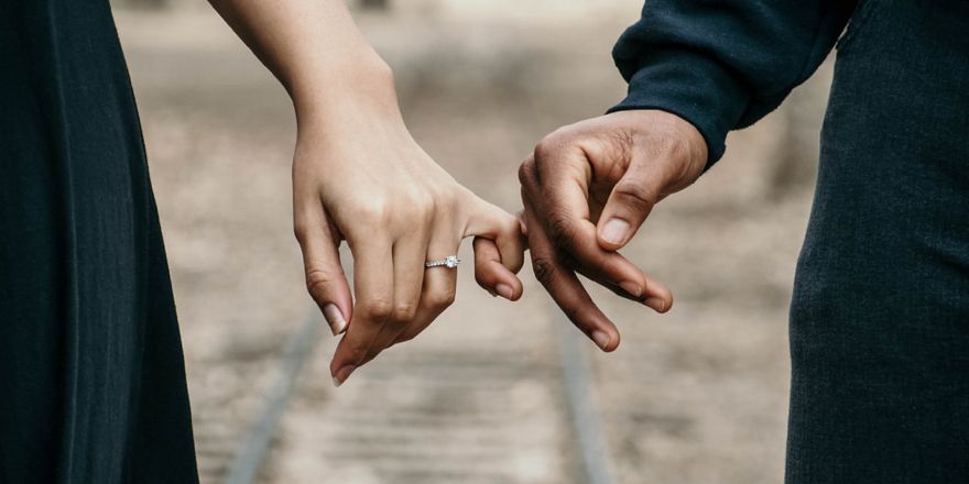 Twee handen houden elkaar vast aan de pink