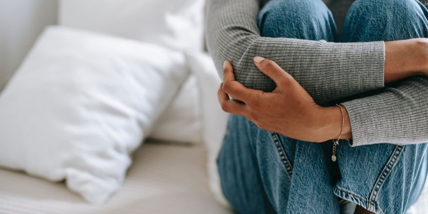 Vrouw heeft armen om haar benen geslagen op bed