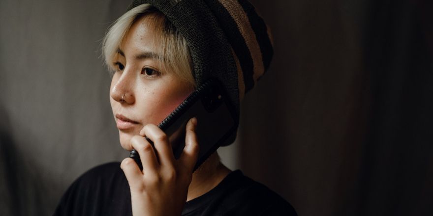 Vrouw tegen een donkere achtergrond heeft een smartphone aan haar oor