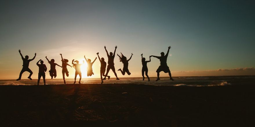 Vrienden springen in de lucht met zonsondergang op de achtergrond