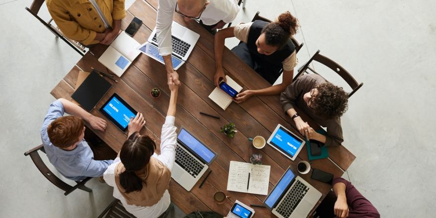 Mensen vergaderen met laptops voor zich, foto van bovenaf