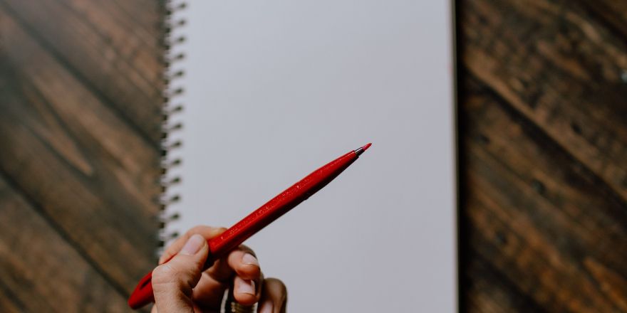 een rode pen voor een leeg notitieblok