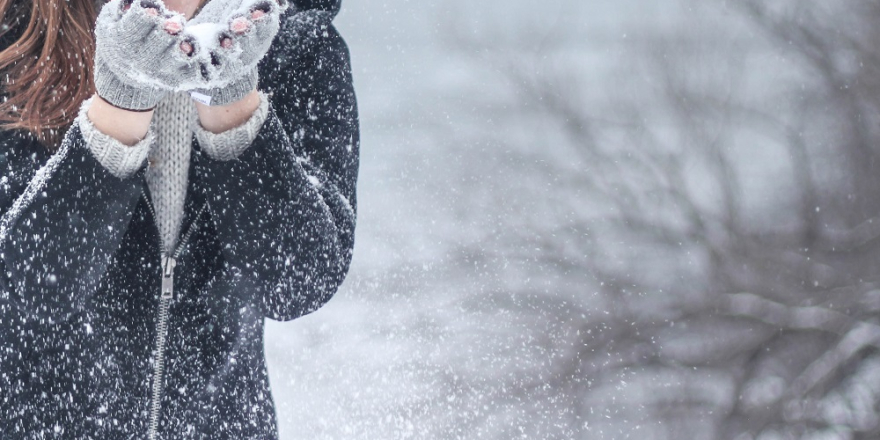 Vrouw blaast sneeuw uit haar handen