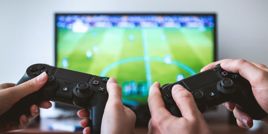 twee mensen houden game controllers vast voor een grote tv