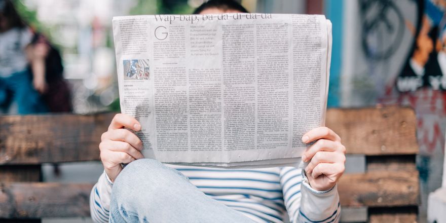 een man die op de bank een krant leest