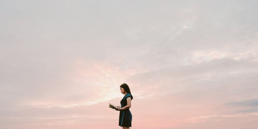 Vrouw die een boek leest voor een opgaande zon