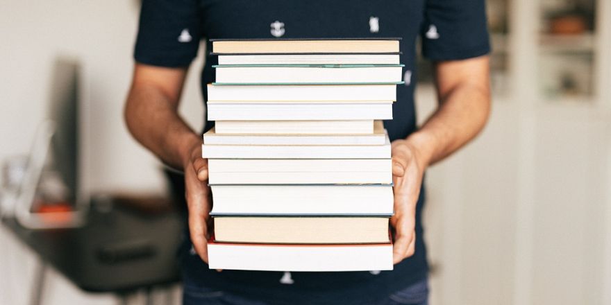 Persoon draagt een stapel boeken