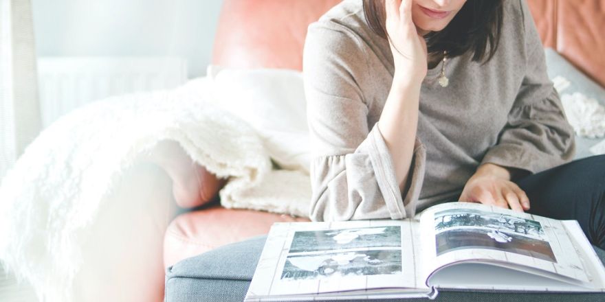 Een vrouw bladert op bed door een groot foto-album