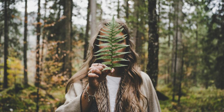 Vrouw houdt blad voor haar gezicht