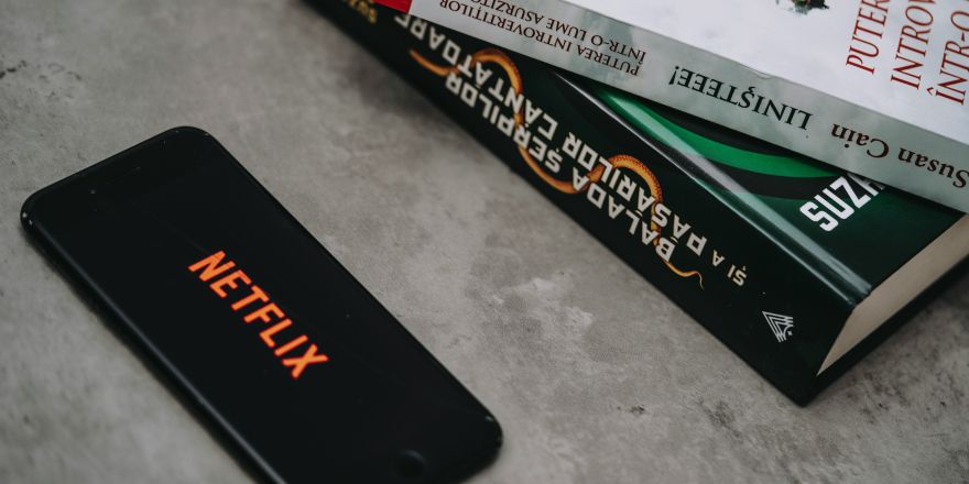 Netflix op mobieltje met stapel boeken ernaast