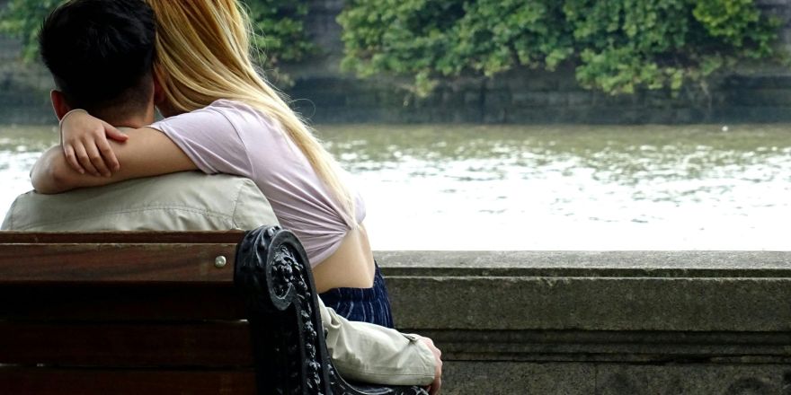 Man en vrouw zitten op een bankje met uitzicht op de rivier