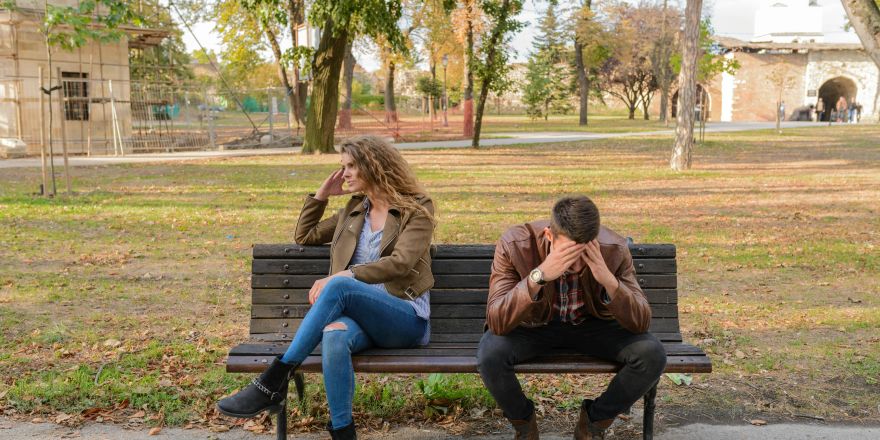 Man en vrouw zitten op een bankje, maar kijken van elkaar weg