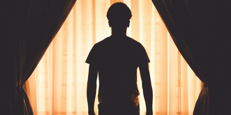 Silhouet van man voor raam met gordijnen