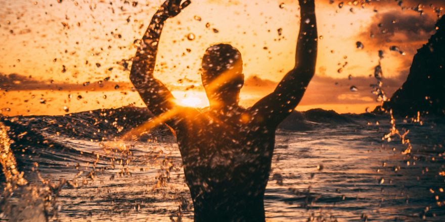 Jongen in de zee met zonsondergang
