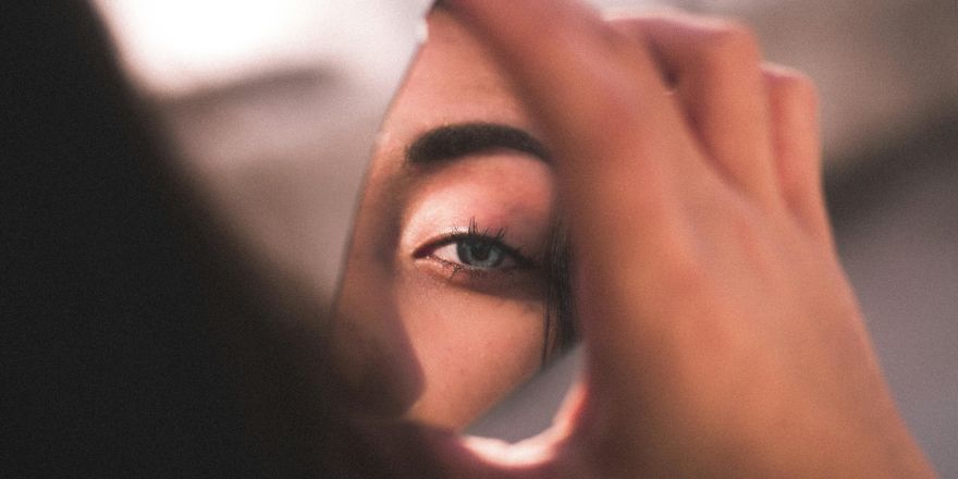 Vrouw kijkt in gebroken spiegel
