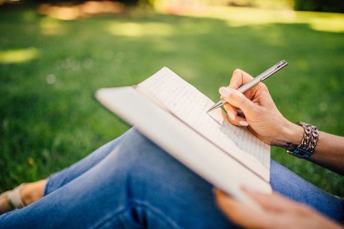 Persoon schrijft in notitieboekje in het park