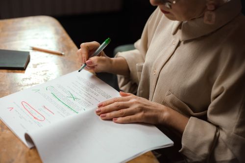 Vrouw redigeert een manuscript met groene en rode pennen