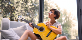 Vrouw schrijft een liedje met een gitaar op schoot