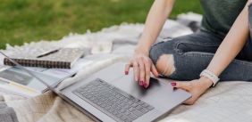 Vrouw tikt op laptop in het gras