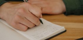 Een man schrijft in een notitieboekje