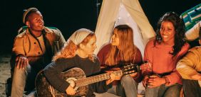 Groep vrienden zingt rond een kampvuur