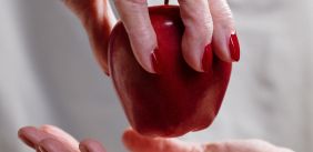Hand geeft een rode appel aan een andere hand