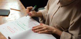 Vrouw redigeert een manuscript met groene en rode pennen