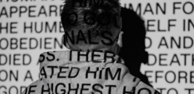 een jongen staat met zijn gezicht naar de muur met geprojecteerde tekst