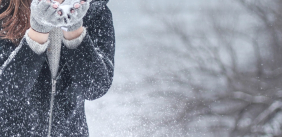 Vrouw blaast sneeuw uit haar handen