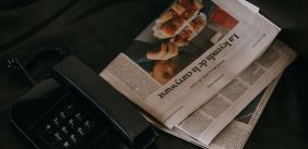 Afbeelding van een dubbelgevouwen krant met daarnaast een huistelefoon