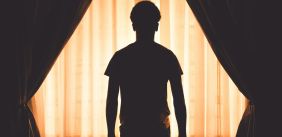 Silhouet van man voor raam met gordijnen