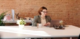 vrouw in rolstoel werkend aan bureau achter een computer