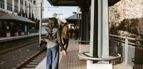 Vrouw In Zwart Jasje En Blauwe Denimjeans Die Zich Op Stoep Bevinden op station