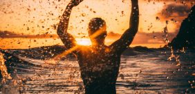 Jongen in de zee met zonsondergang