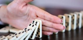 Hand tussen omvallende dominosteentjes