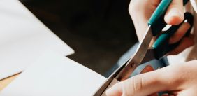 Persoon knipt met een schaar in wit papier