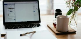 Laptop met open notebook ervoor en een kop ernaast
