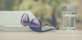 zonnebril op boek met glas water ernaast