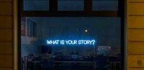 Neon letters 'what is your story' hangt in een raam